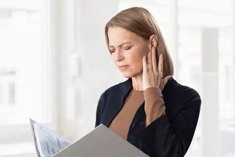 Frau hält sich das Ohr wegen Ohrgeräuschen