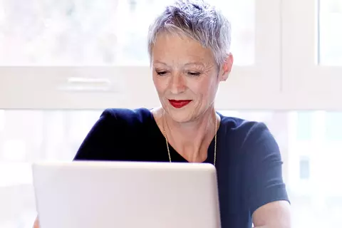 Frau schaut in ihren Laptop und schreibt