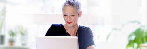 Frau schaut in ihren Laptop und schreibt