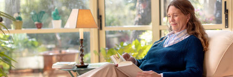 Frau liest ein Buch und informiert sich über die Ursachen von Vergesslichkeit