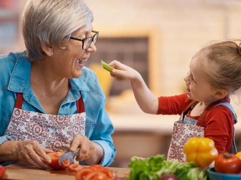 Eine ältere Dame und ihre Enkelin schneiden gemeinsam Gemüse