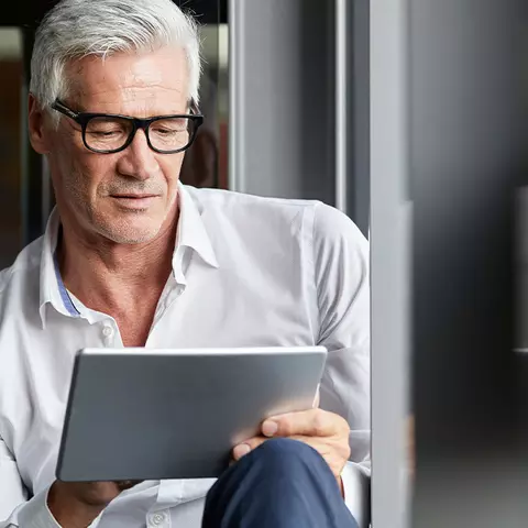 Mann möchte seine Vergesslichkeit behandeln und informiert sich hierüber im Internet über sein Tablet.