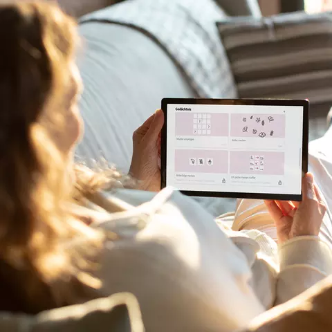 Frau hält sich geistig fit mit Gedächtnisübungen am Tablet