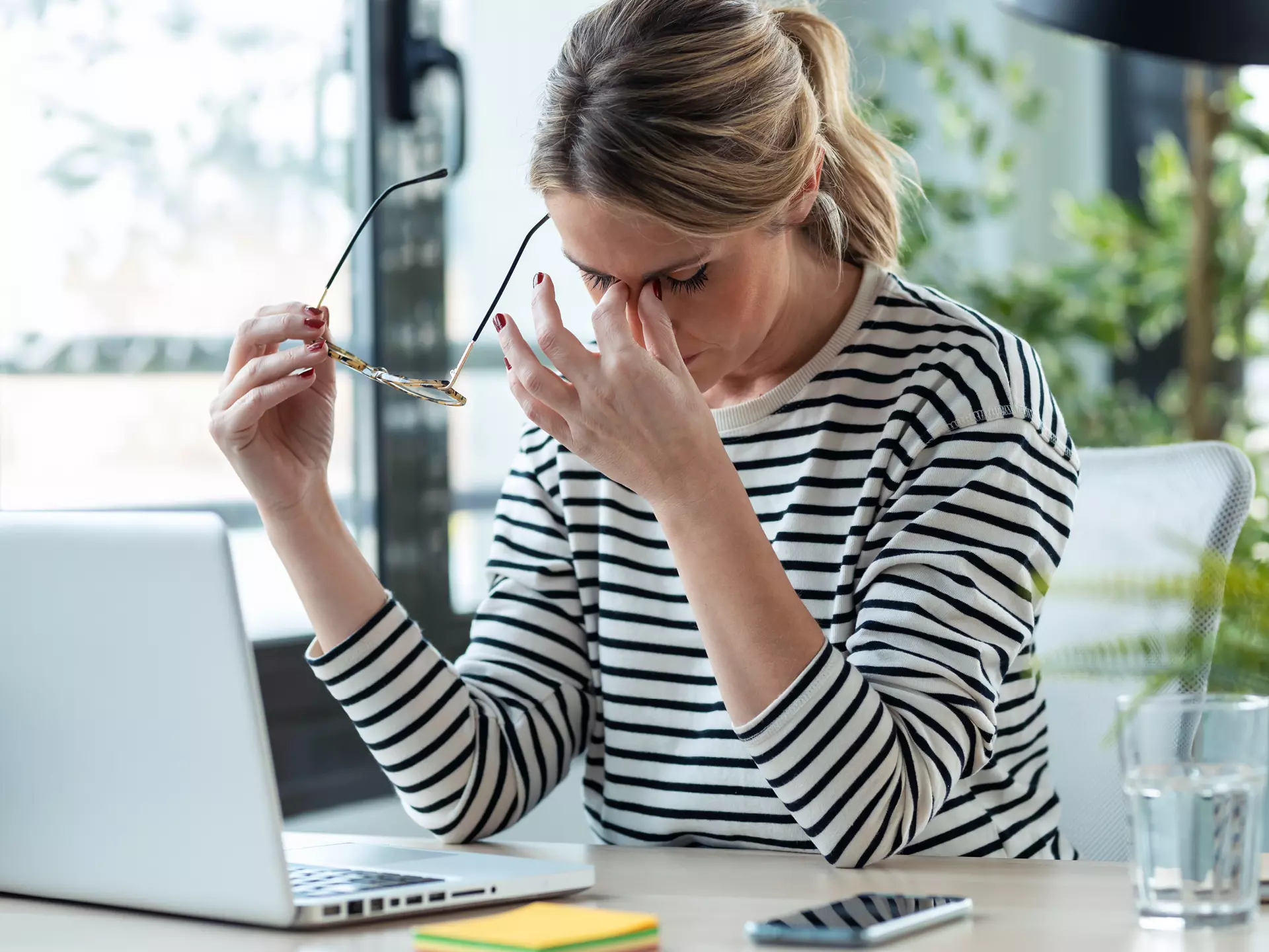Frau sitzt vor ihrem Laptop und reibt sich die Augen